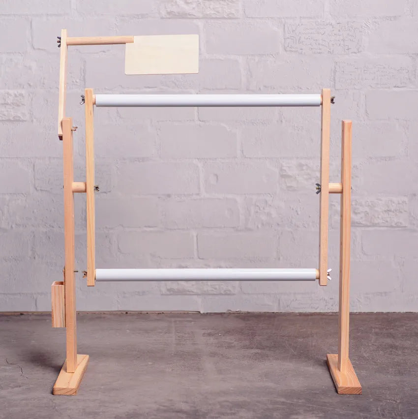 Vertical solid pine wood desktop embroidery frame with height adjustment mechanism in a natural log colour.
