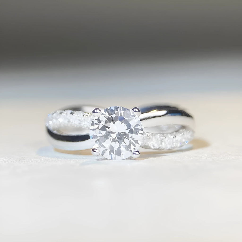 Silver geometric cross ring with a 1 carat moissanite in a four-claw twisted arm setting.