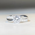 Silver geometric cross ring with a 1 carat moissanite in a four-claw twisted arm setting.