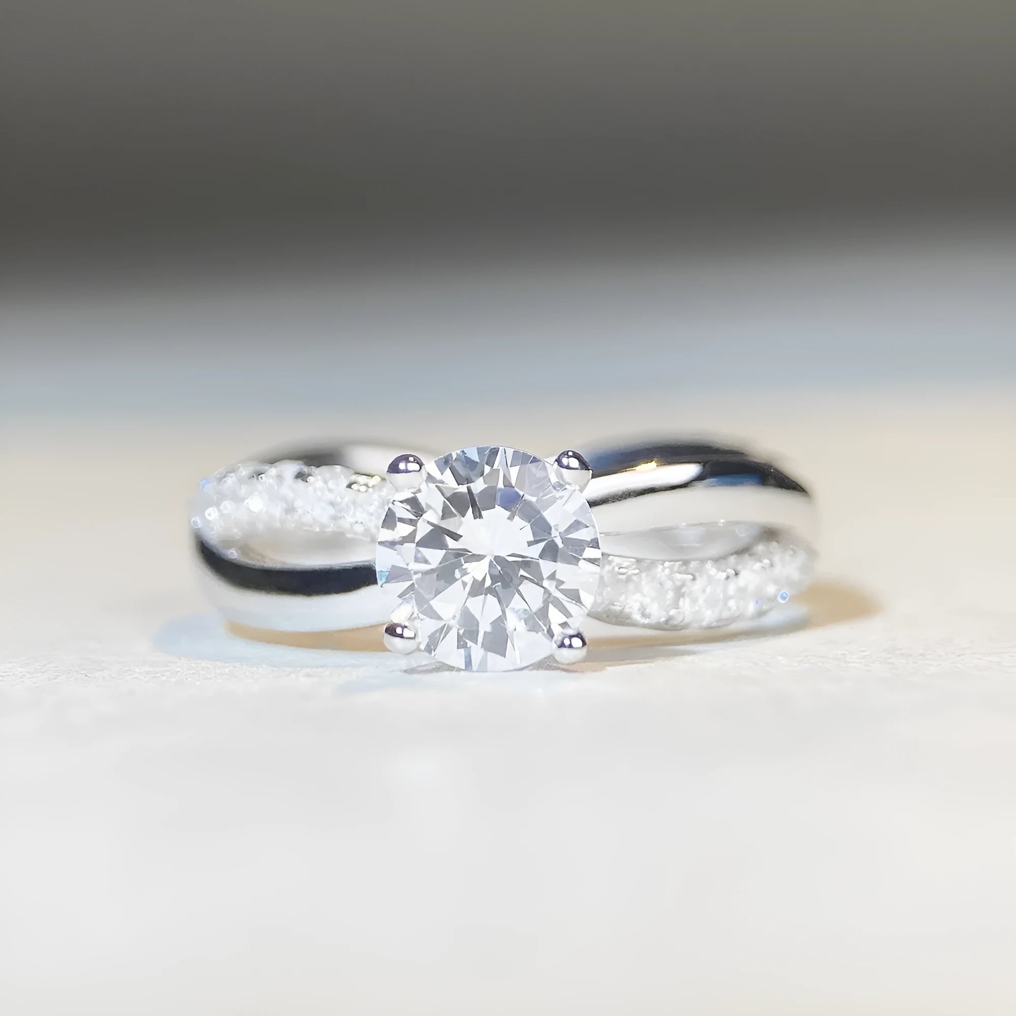Silver geometric cross ring with a 1 carat moissanite in a four-claw twisted arm setting.
