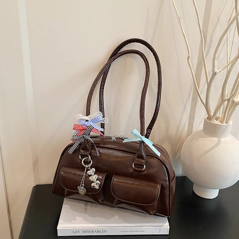 Brown PU leather women's pillow flap bag with double straps and a decorative ribbon pendant.