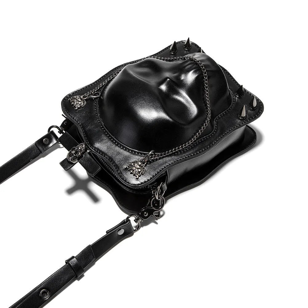 Black mini square crossbody bag with embossed skull design, metal chain strap, rivets, and contrast stitching.