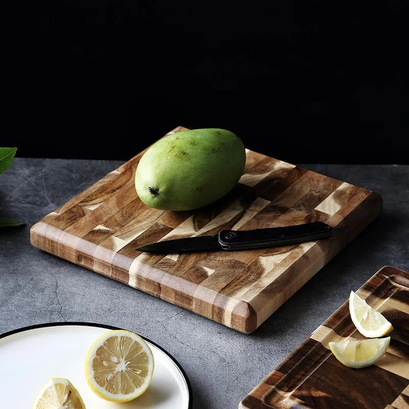 Brown solid acacia wood cutting board with 3cm thickness on a kitchen counter.