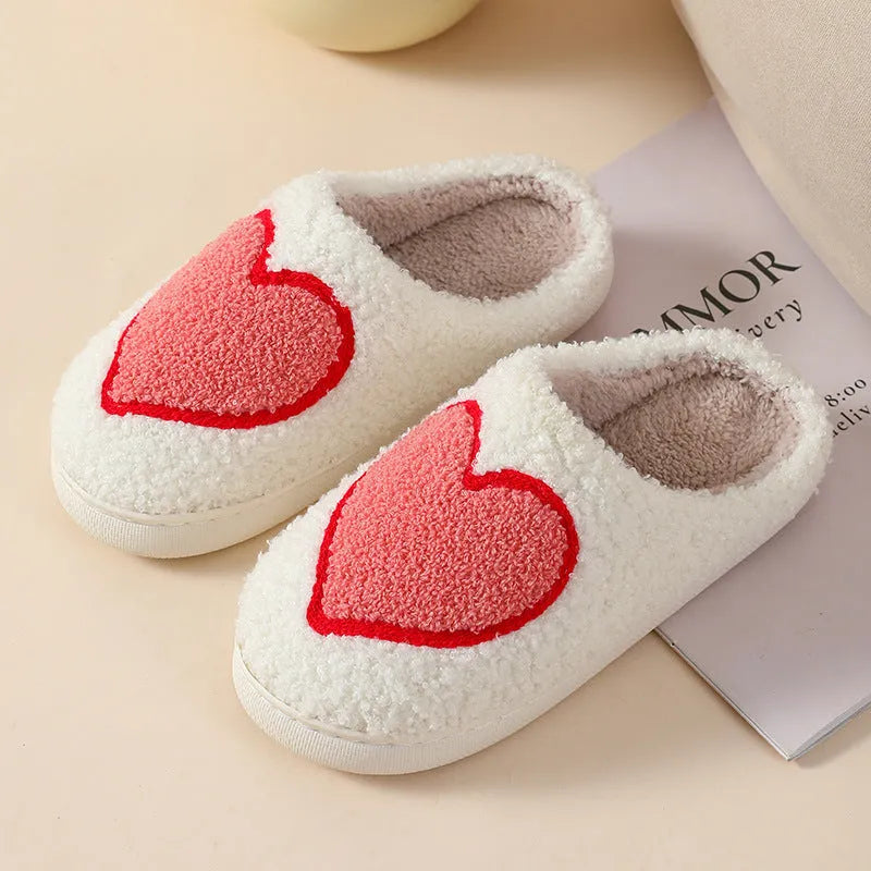 Women's plush home slippers in cartoon love style print with round toe and non-slip PVC sole.