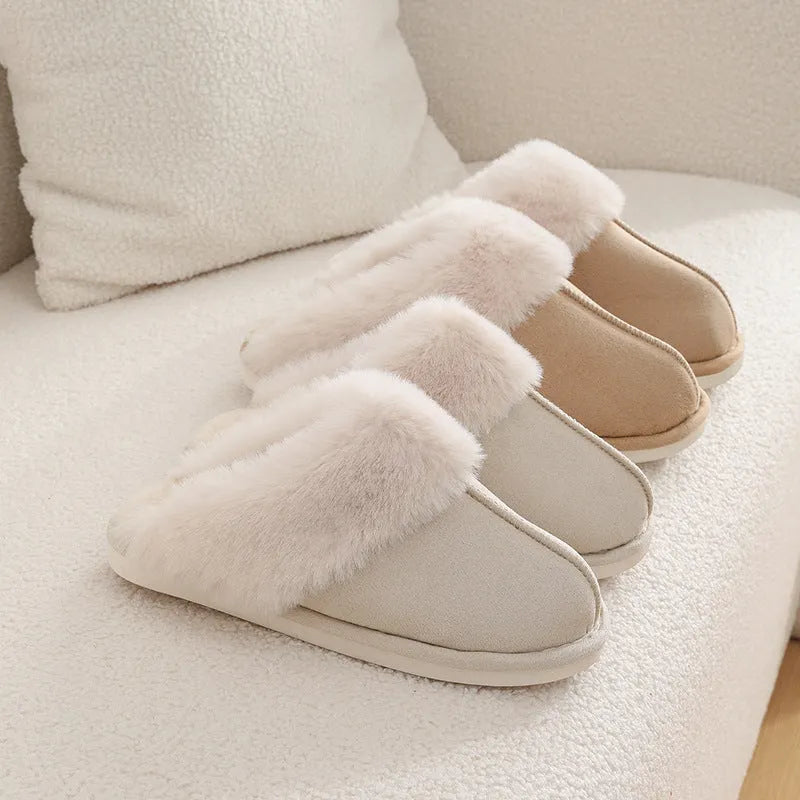 Women's brown plush winter slippers with round toe and flat heel on a wooden floor.