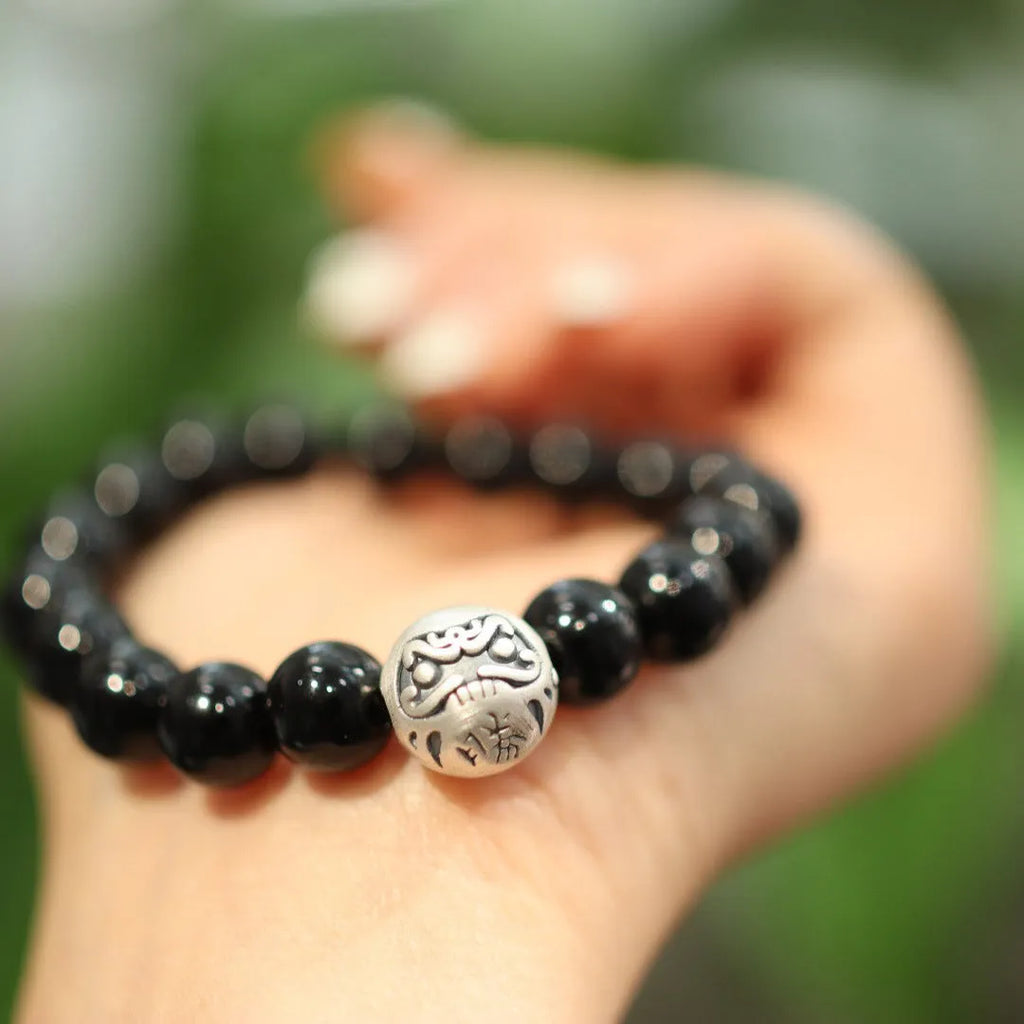 Close-up of a black agate and sterling silver bracelet with 10mm beads and a manual polish finish.