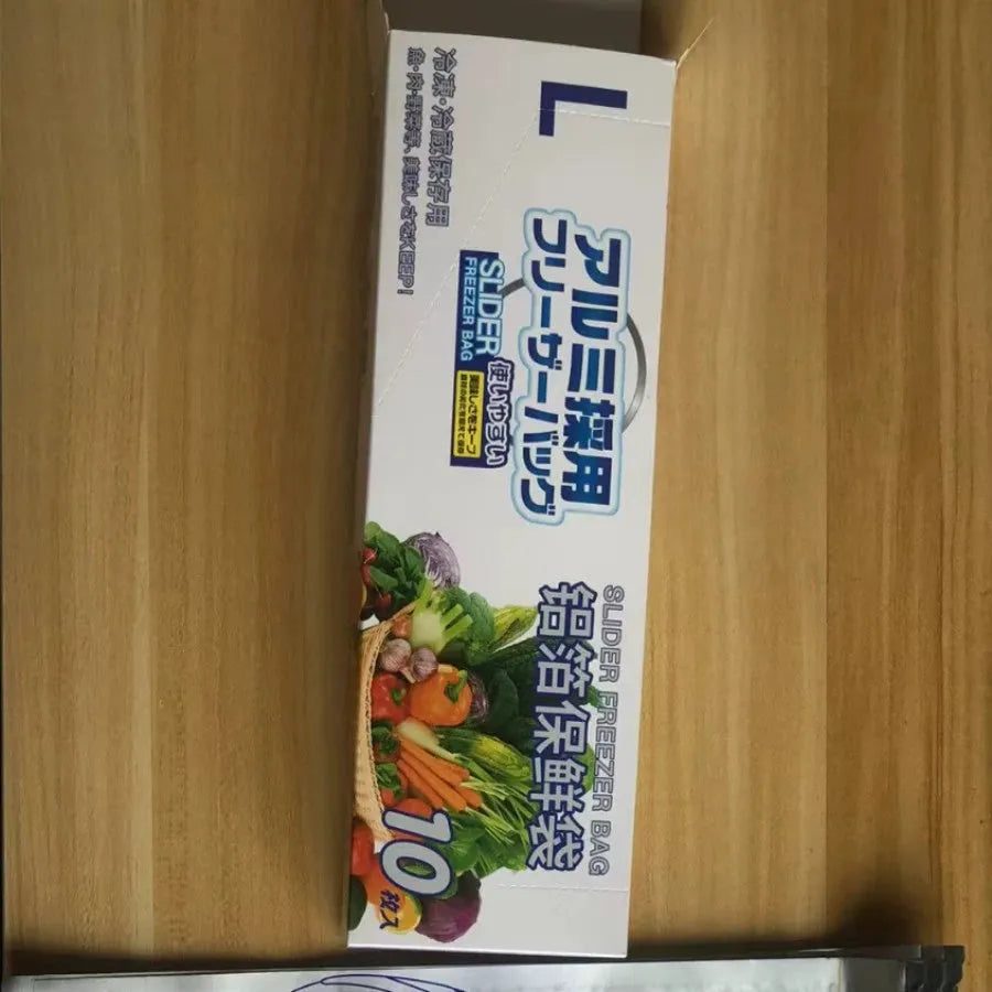 Set of aluminium foil sealed food storage bags and boxes in three different sizes on a kitchen counter.