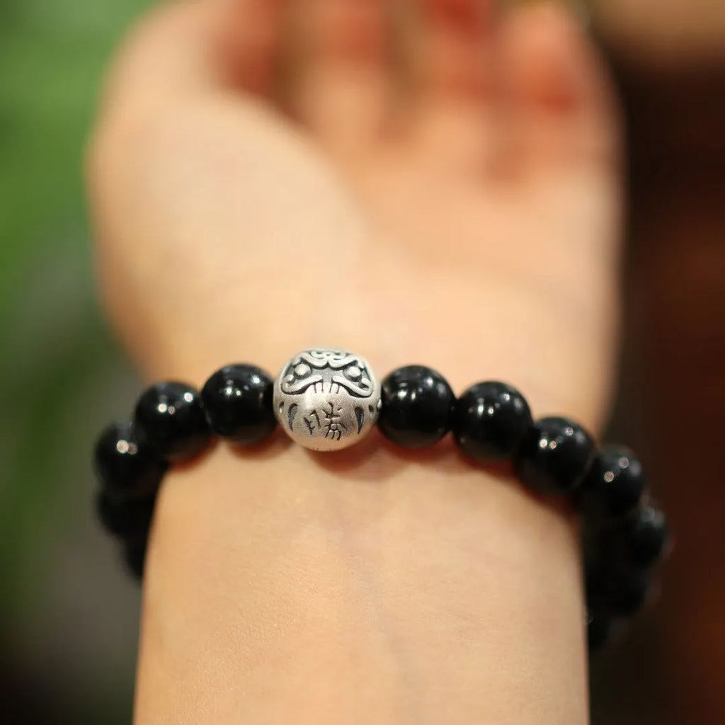 Close-up of a black agate and sterling silver bracelet with 10mm beads and a manual polish finish.