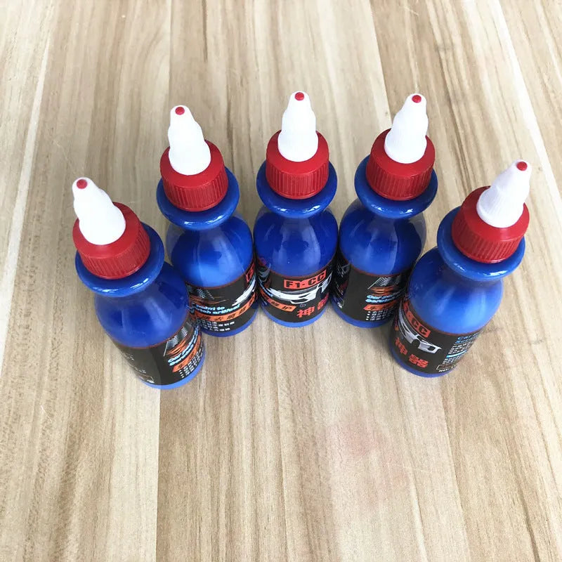 Small blue car scratch repair agent bottle with integrated wiping tool for automotive paintwork