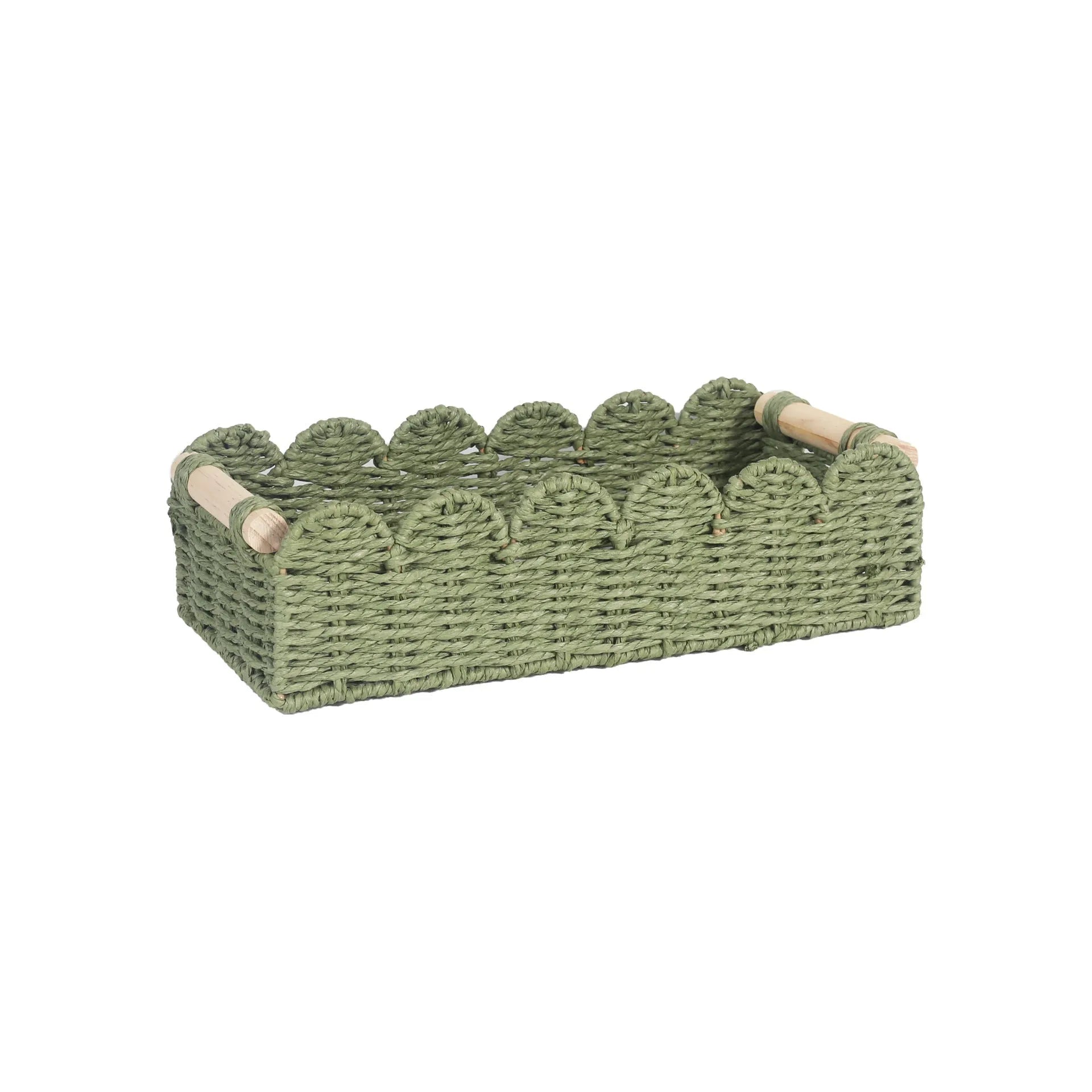 A woven paper storage basket in a neutral colour on a wooden desktop, holding remote controls and pens.