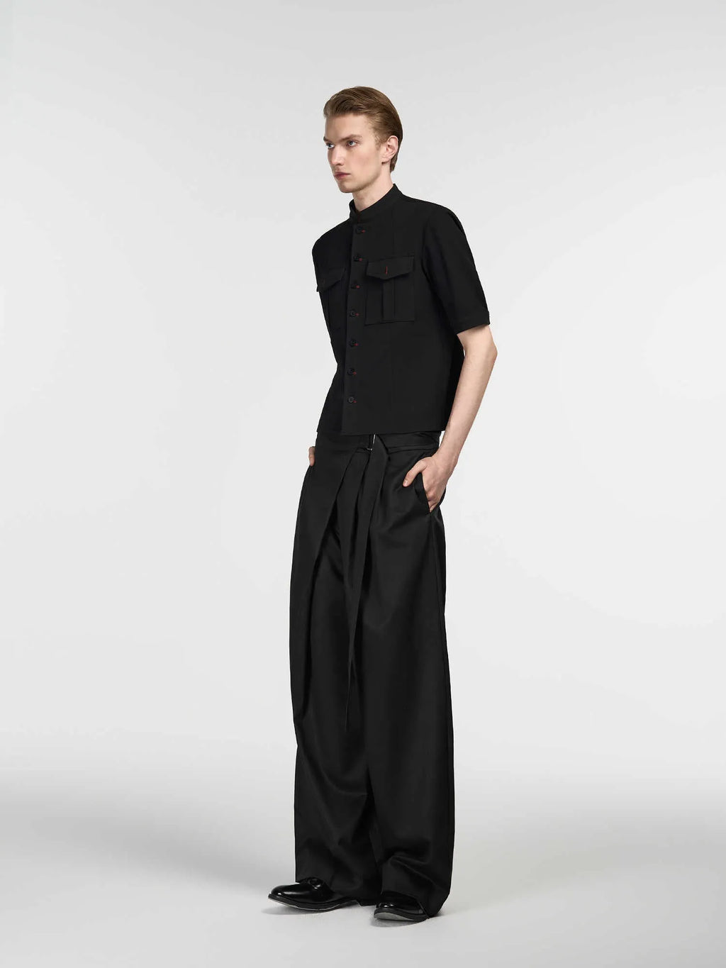 Black loose-fit straight-leg trousers with a single pleat and adjustable mid waist on a hanger.