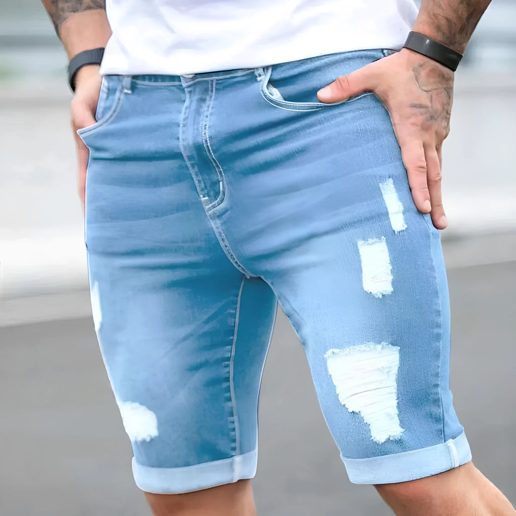 Men's sky blue denim shorts with distressed multi-hole design, low waist, and zip fly opening