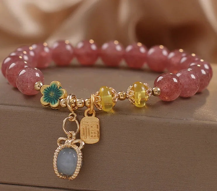 Red strawberry quartz beaded bracelet with silver-toned alloy charms and clear rhinestone details.