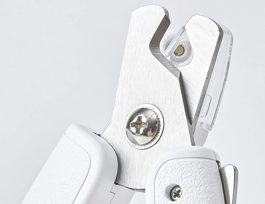 White LED pet nail clippers with transparent guard open, showing triangular steel blades and a nail file.