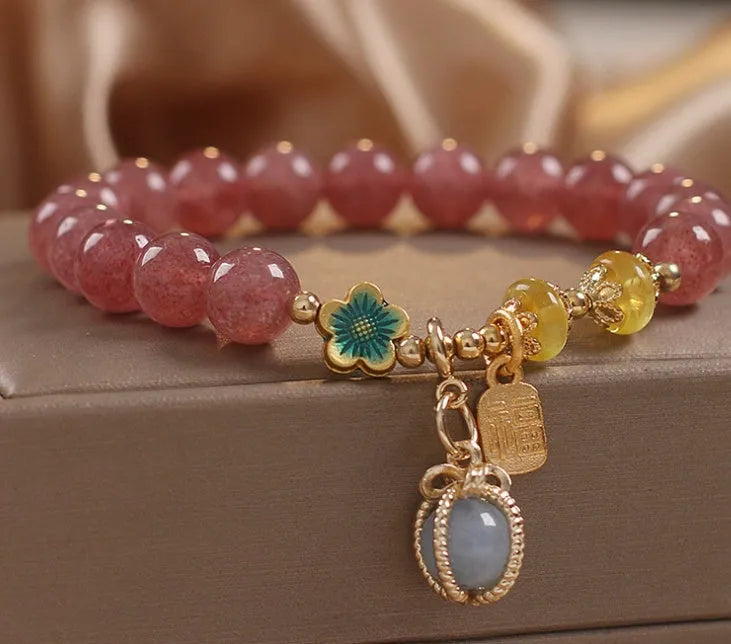 Red strawberry quartz beaded bracelet with silver-toned alloy charms and clear rhinestone details.
