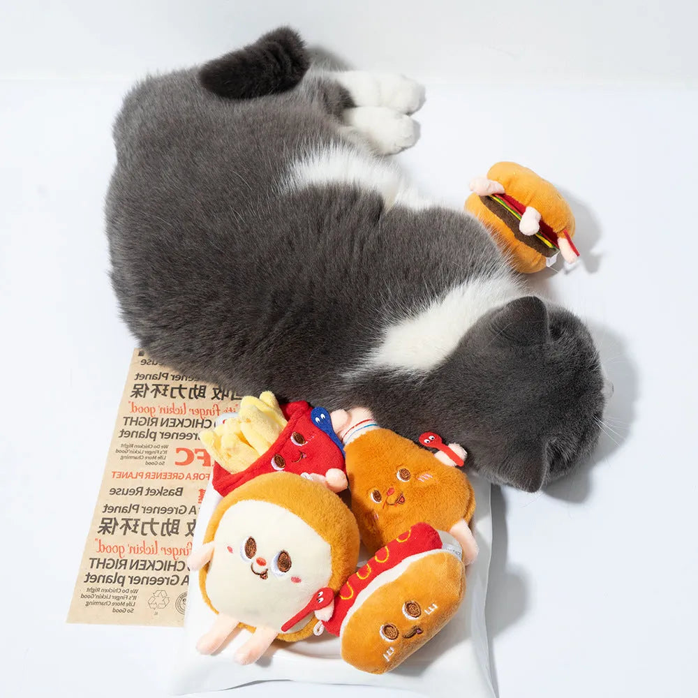 Set of four soft fabric cat chew toys shaped like a hamburger, chicken leg, fries, and hot dog on a plain background.