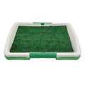 Green three-layer indoor dog toilet tray with artificial grass top, absorbent pad, and plastic drip tray base.
