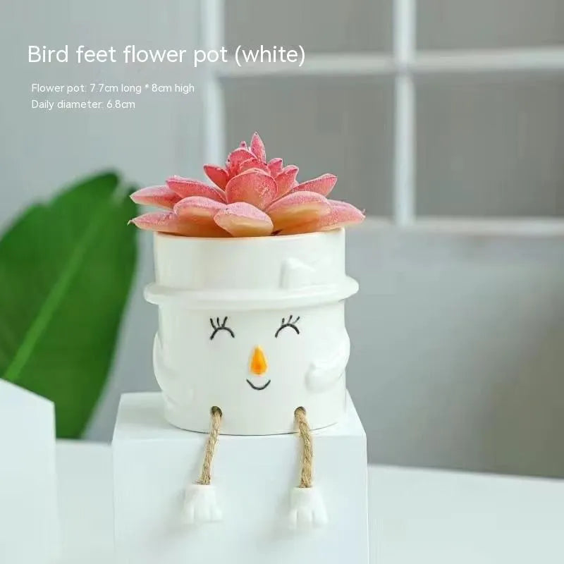 Ceramic cartoon-style hanging foot flowerpot for succulent plants on a desktop.