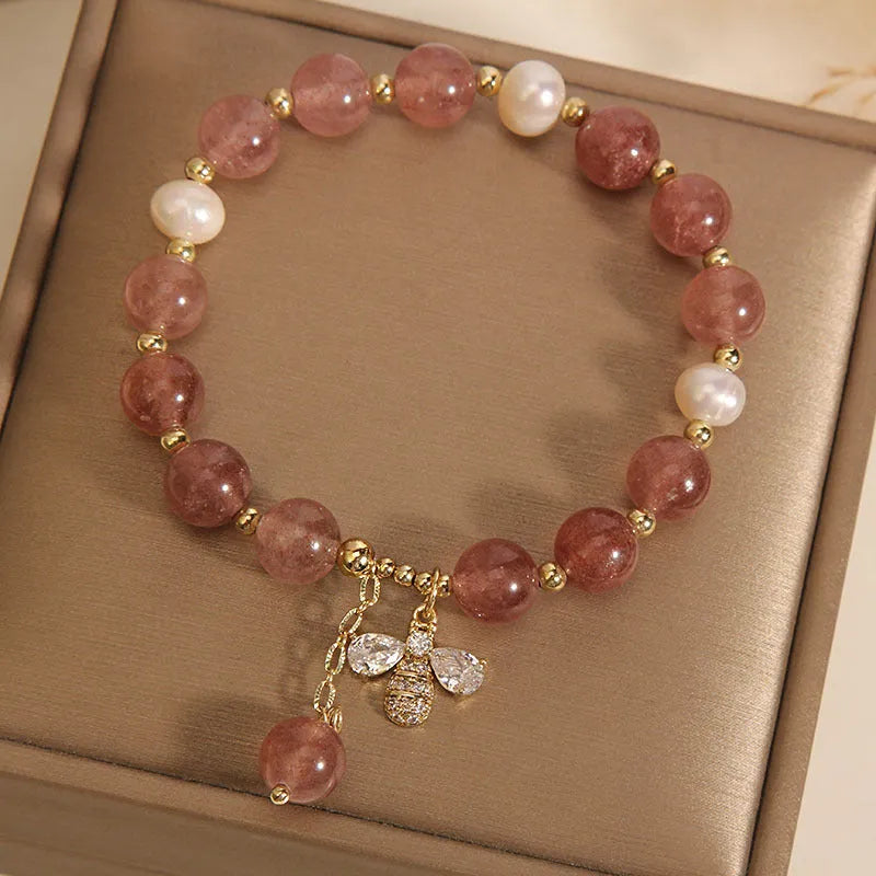 Close-up of a women's bracelet with pink strawberry quartz stones, white freshwater pearls, and sparkling zircon accents on an alloy clasp.