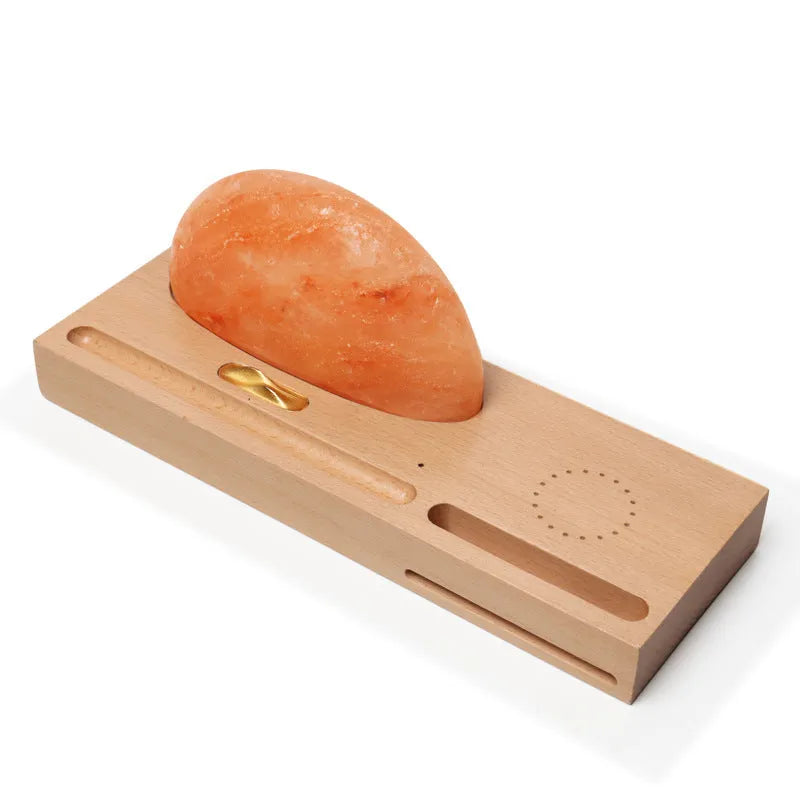Natural crystal salt lamp with wireless charging pad on a light beech wood table base.