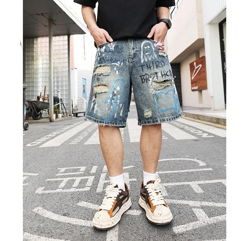 Blue ripped men's denim shorts with graffiti print and straight-leg cut.