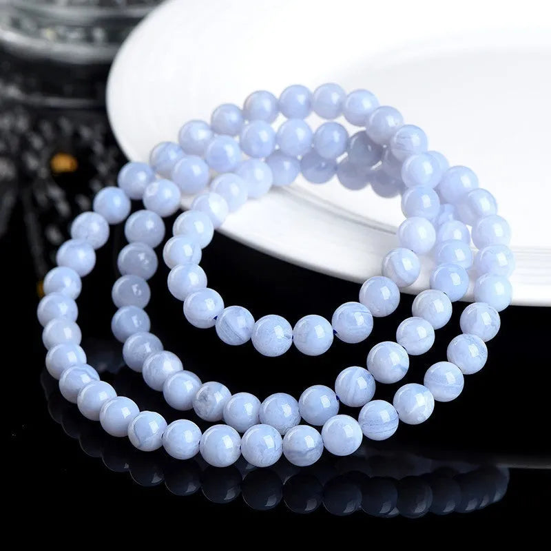 Close-up of a blue agate bracelet with multi-circle patterns, striped beads, and a Ruyi element on a neutral background.