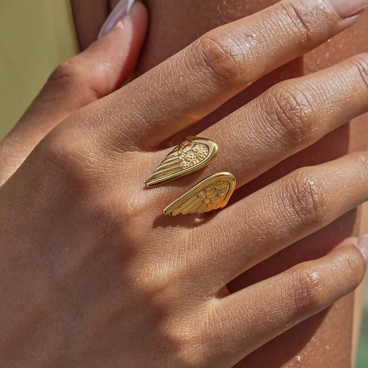 Silver wings design opening ring made of stainless steel on a plain background.