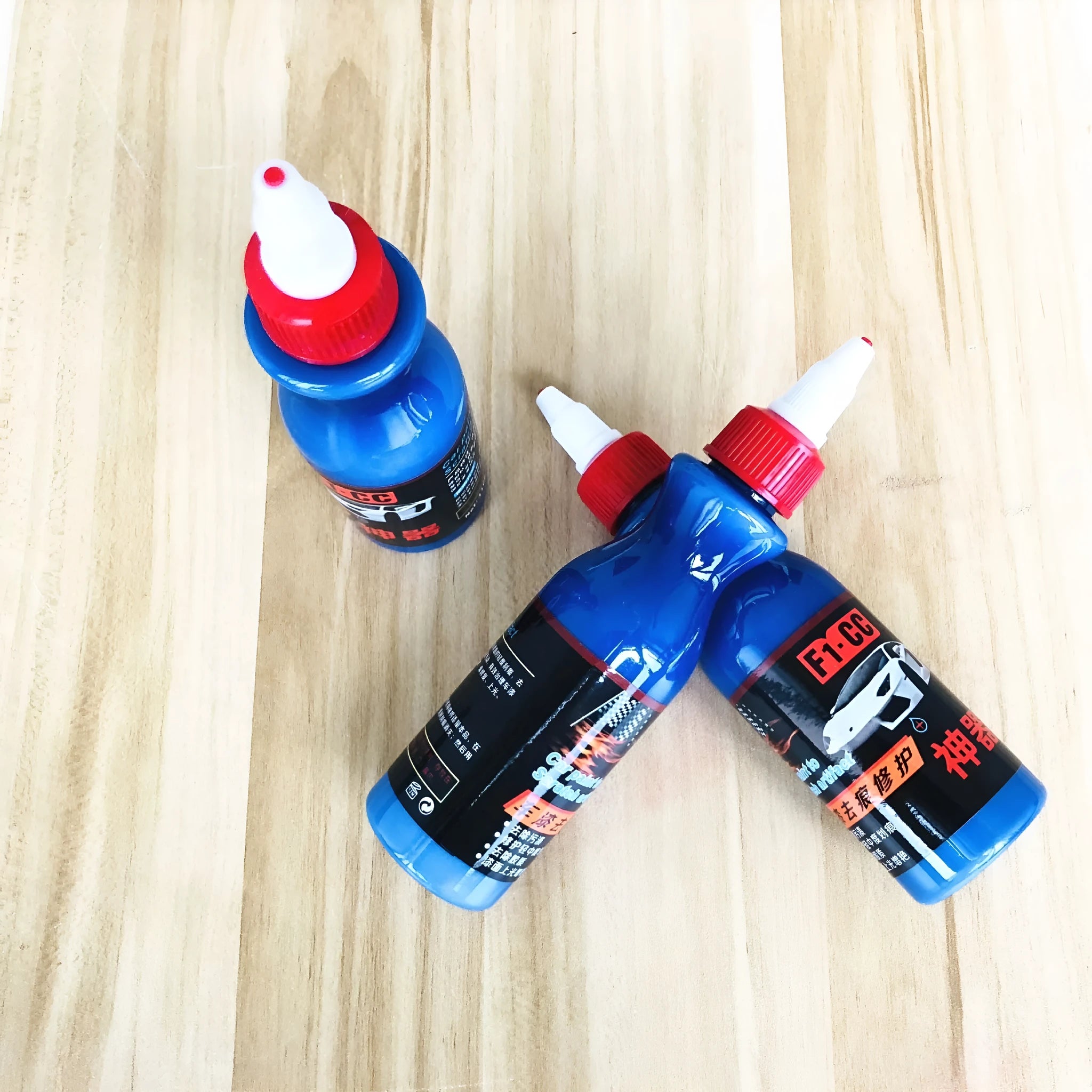 Small blue car scratch repair agent bottle with integrated wiping tool for automotive paintwork