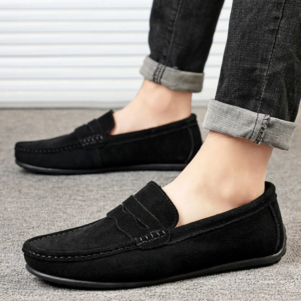 Men's solid colour suede loafers with a round toe and flat rubber sole on a neutral background.