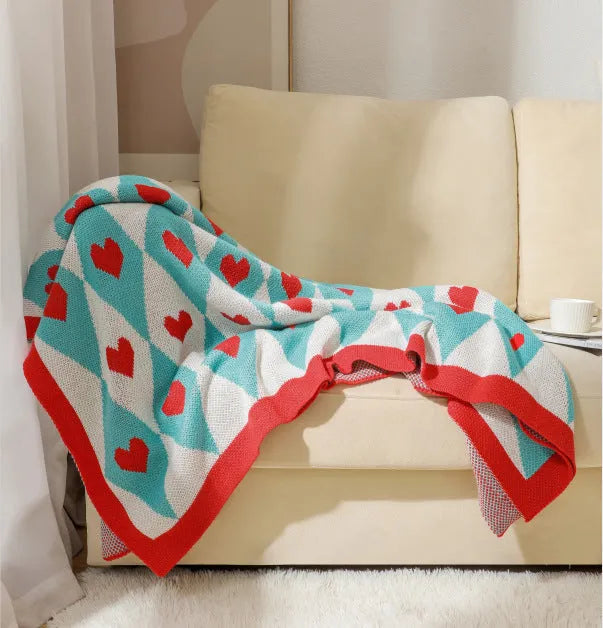 Bohemian style acrylic blanket with tassel fringe on a sofa, shown in a geometric print colour.
