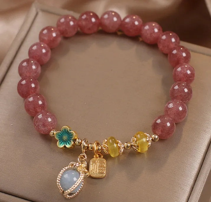 Red strawberry quartz beaded bracelet with silver-toned alloy charms and clear rhinestone details.