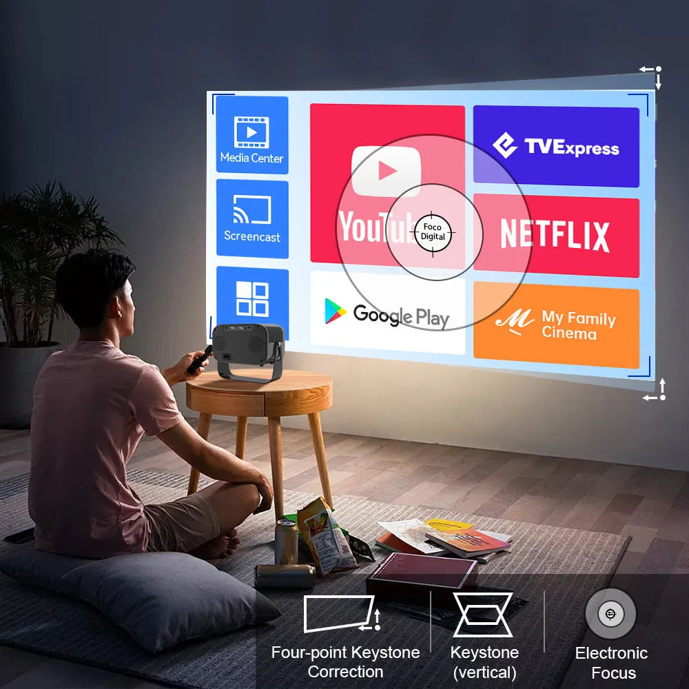 Black portable smart projector with remote control and cables on desk