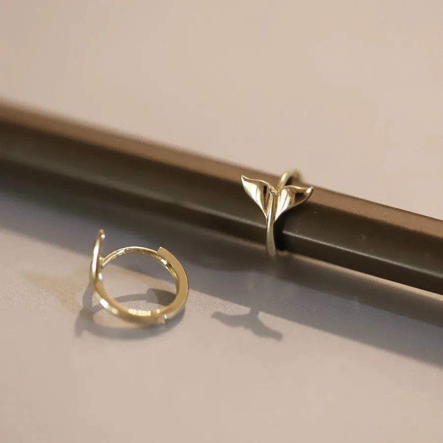 S925 sterling silver fishtail hoop earrings in gold colour on a white background.