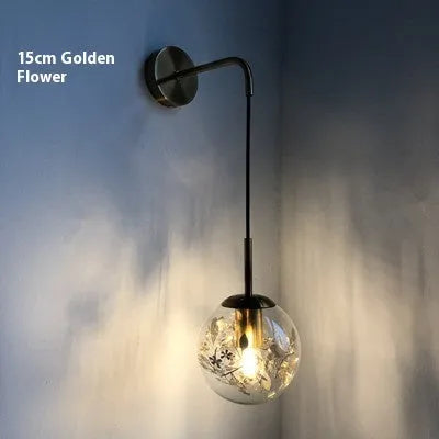Small modern glass wall lamp in golden flower or silver flower finish for bedside lighting.