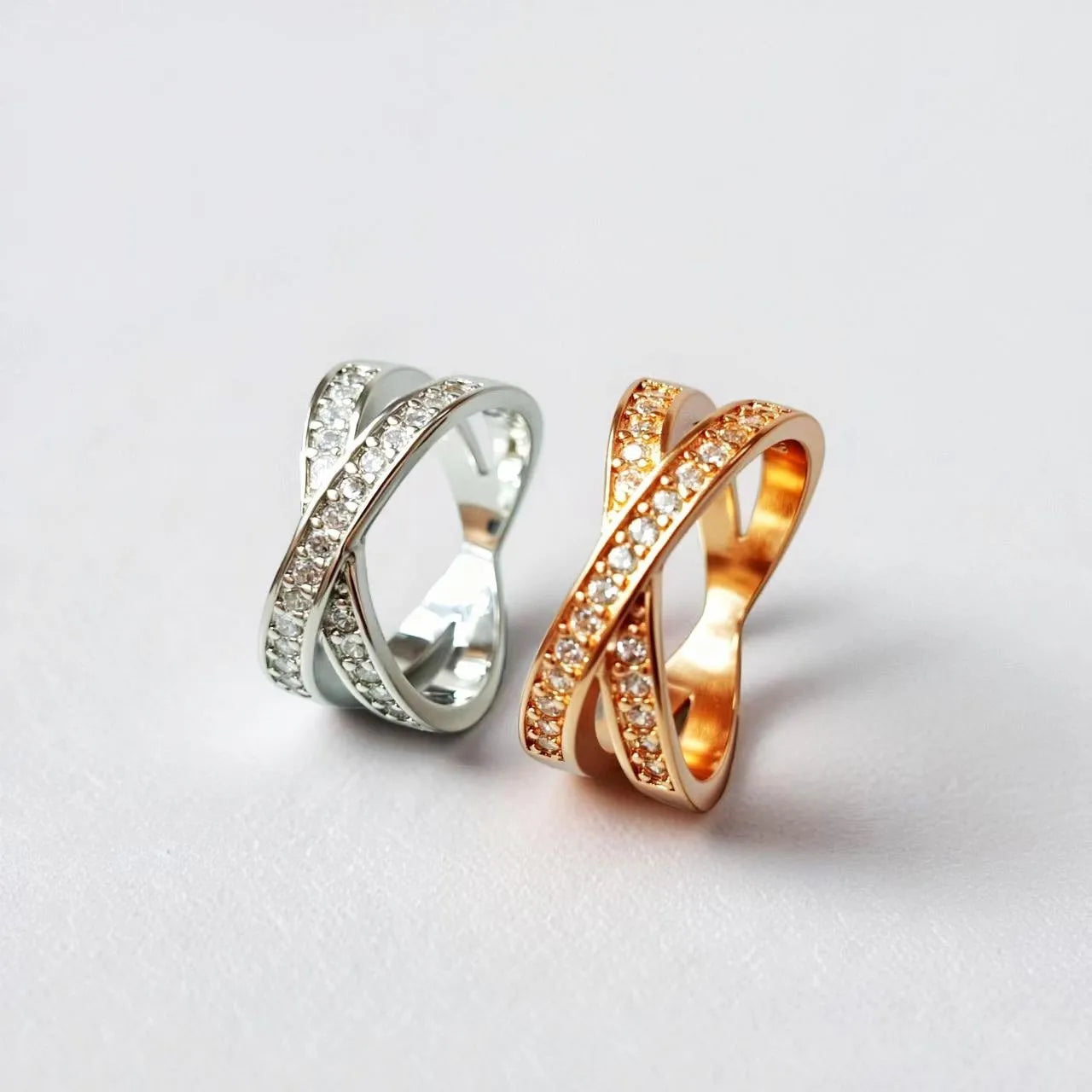 Simple metal cross ring with micro-inlaid zircon detail in silver or rose gold on a finger.