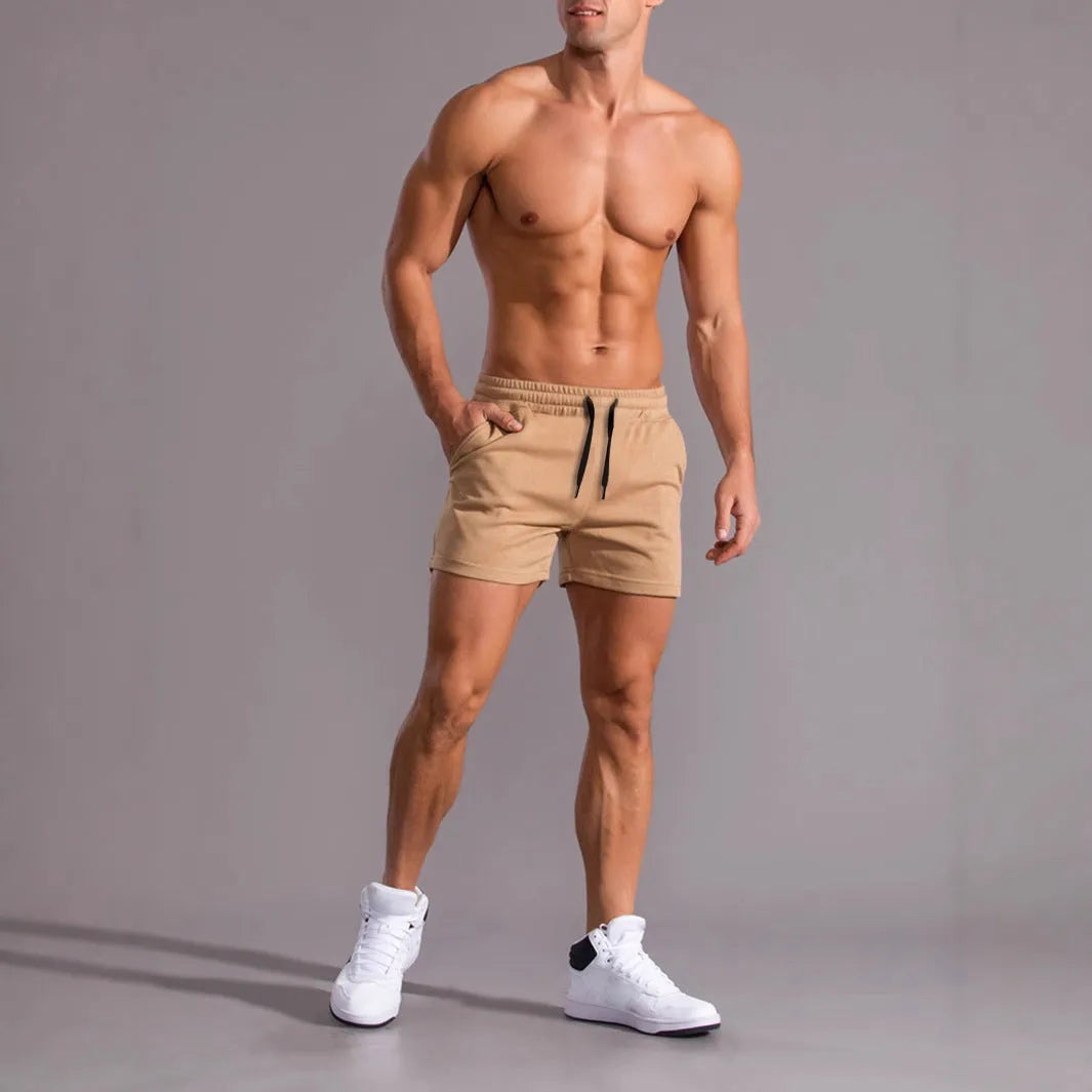 Three pairs of men's solid colour loose fit drawstring shorts in black, khaki, and light brown laid flat
