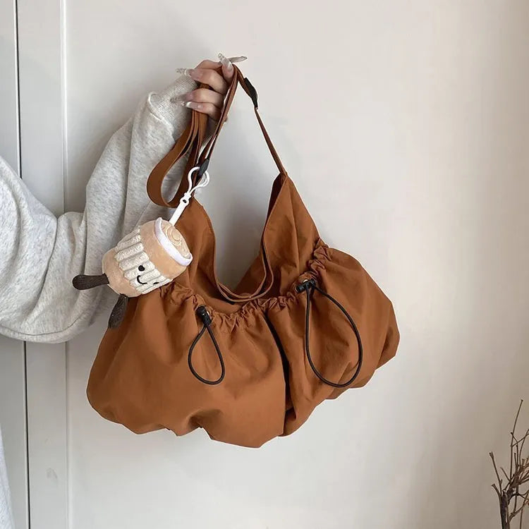 Soft green pleated polyester crossbody bag folded next to a mobile phone showing internal pocket.