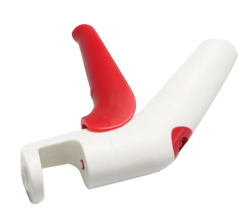 Cherry stoner tool with stainless steel pitting head and white plastic handle on a wooden surface.