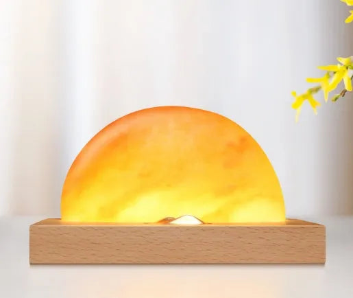 Natural crystal salt lamp with wireless charging pad on a light beech wood table base.
