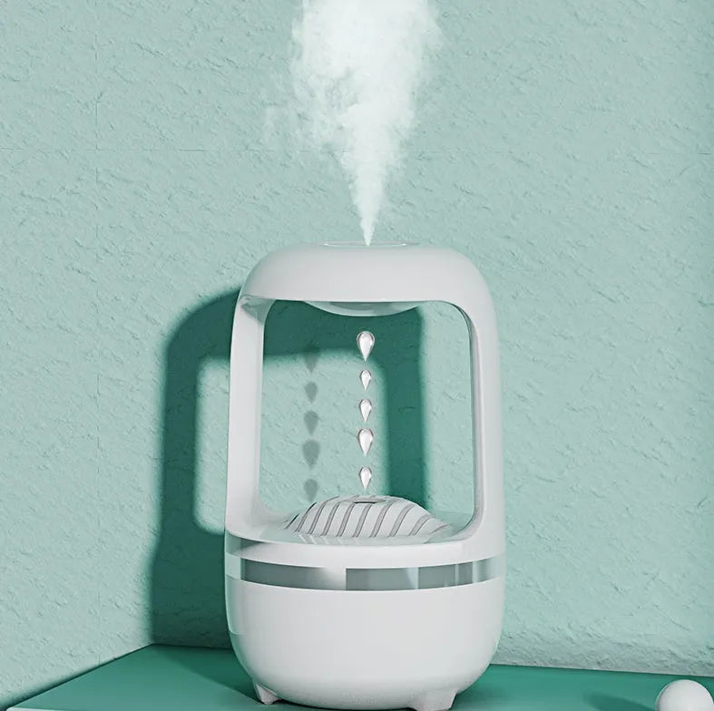 White anti-gravity humidifier on a table showing floating water droplets above its tank.