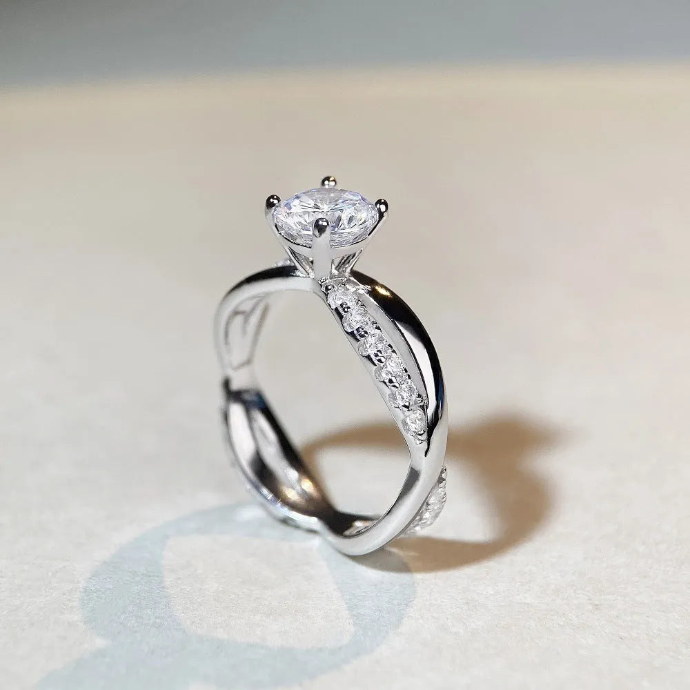 Silver geometric cross ring with a 1 carat moissanite in a four-claw twisted arm setting.