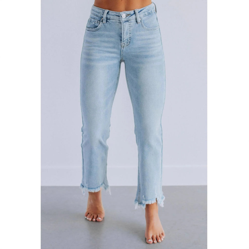 Solid colour women's denim trousers with hand-worn distressing on a hanger.