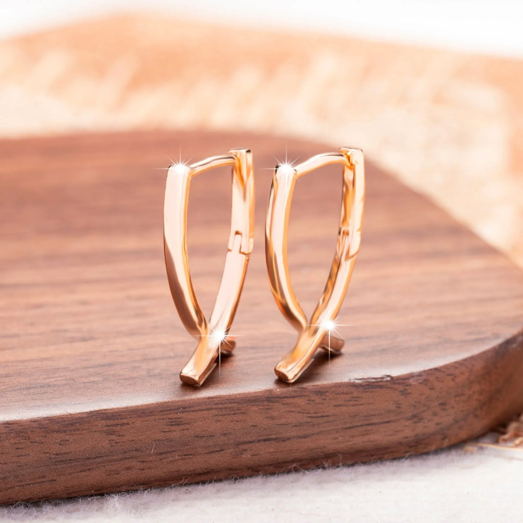 Rose gold cross shaped earrings with copper construction and light luxury aesthetic