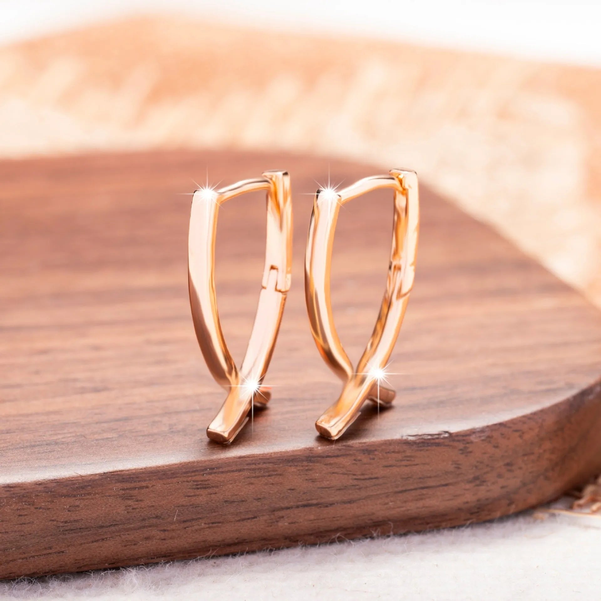 Rose gold cross shaped earrings with copper construction and light luxury aesthetic