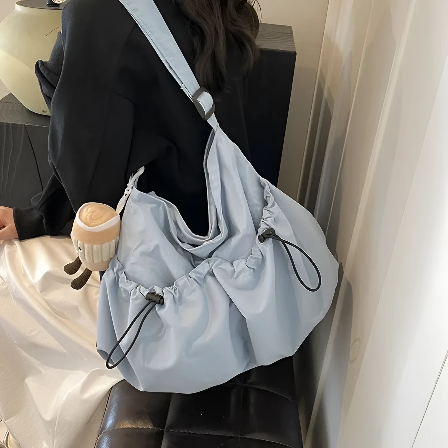 Soft green pleated polyester crossbody bag folded next to a mobile phone showing internal pocket.