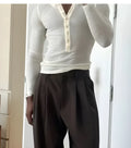 Men's cream coloured ribbed long sleeve henley top on a hanger, showing three-button placket.