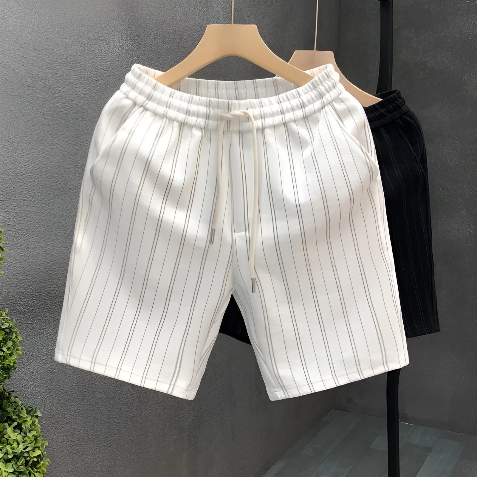 Men's black and white striped casual shorts with elastic waistband showing straight-leg design