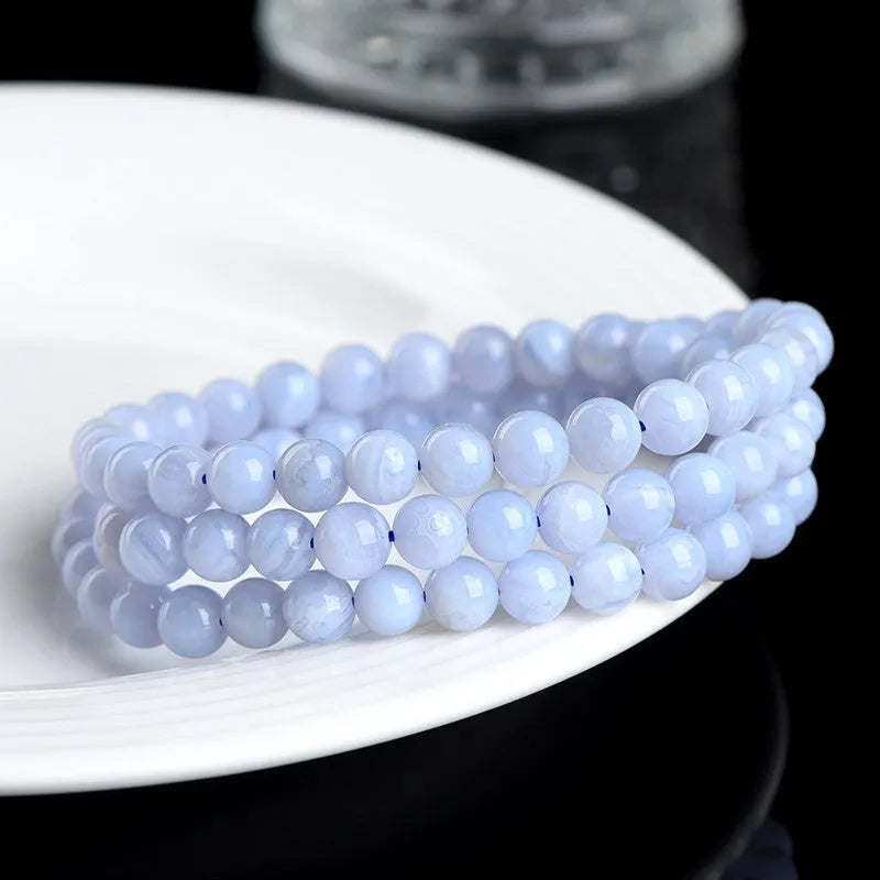 Close-up of a blue agate bracelet with multi-circle patterns, striped beads, and a Ruyi element on a neutral background.