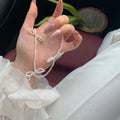 White imitation pearl necklace with a central bow pendant on a chain, adjustable from 31cm to 40cm.