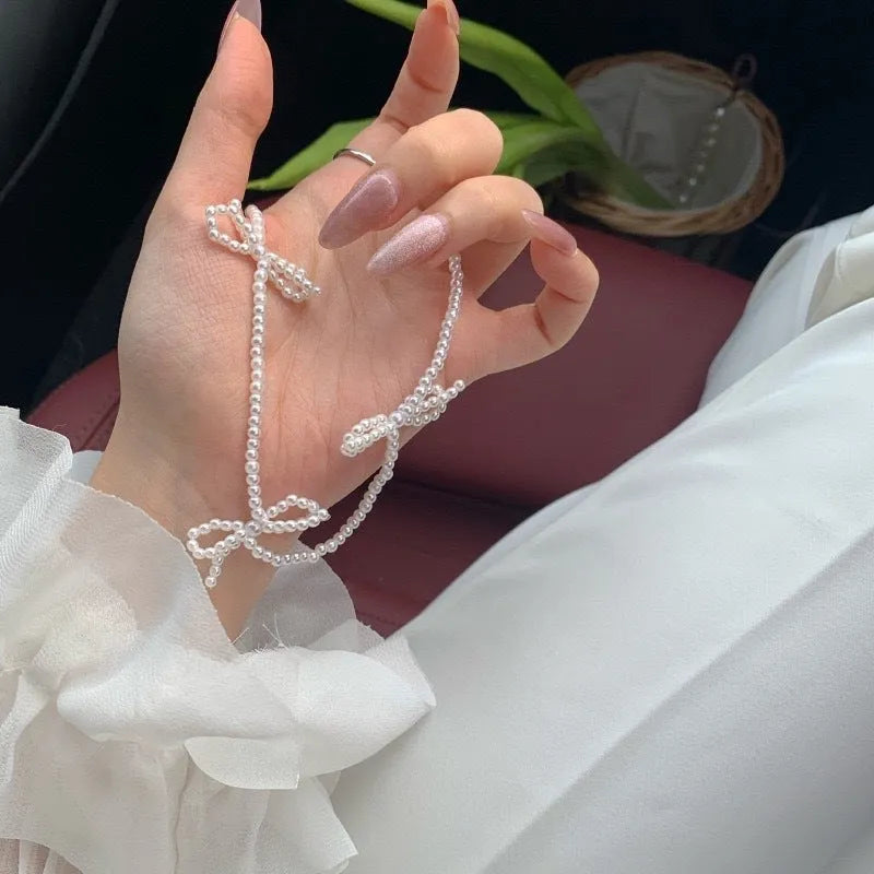 White imitation pearl necklace with a central bow pendant on a chain, adjustable from 31cm to 40cm.